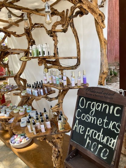 Display of organic cosmetics with a sign indicating 'Organic Cosmetics Are Produced Here' in a rustic setting.