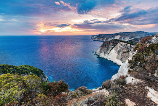 Scenic view of a coastal landscape with cliffs and ocean at sunset.