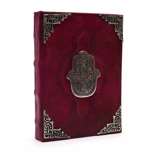 Red leather notebook with Hamsa design and metallic embellishments on a white background