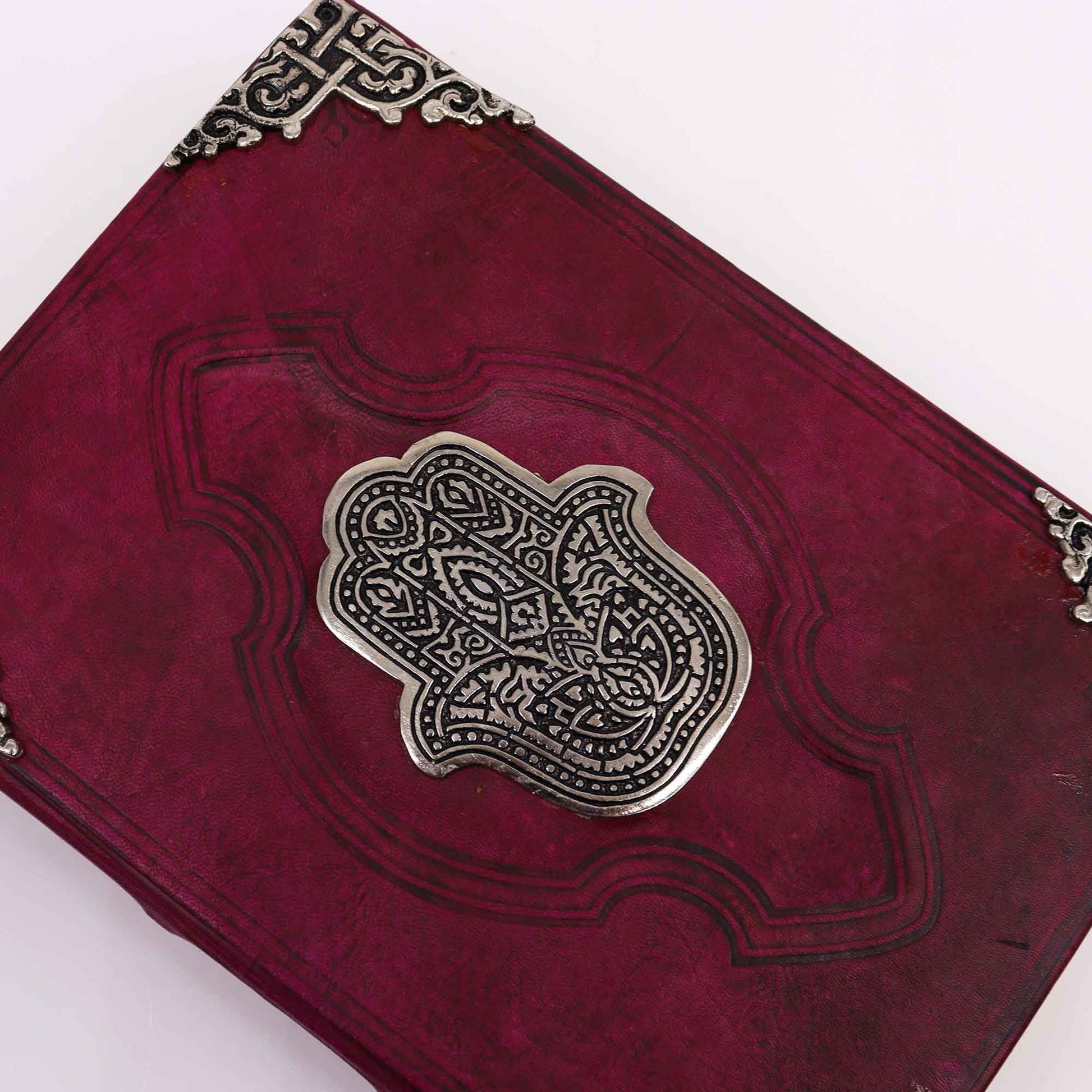 Red leather-bound book with silver embossed design on a white background