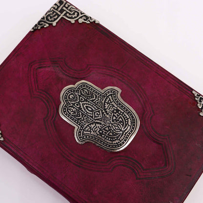 Red leather-bound book with silver embossed design on a white background