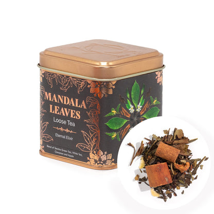 Mandala Leaves Eternal Elixir loose tea in a bronze tin with a dark label, beside a pile of tea leaves, cinnamon, and apple pieces.