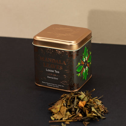 Bronze-lidded tea tin with "Mandala Leaves" label, green mandala, and loose green and white tea blend.