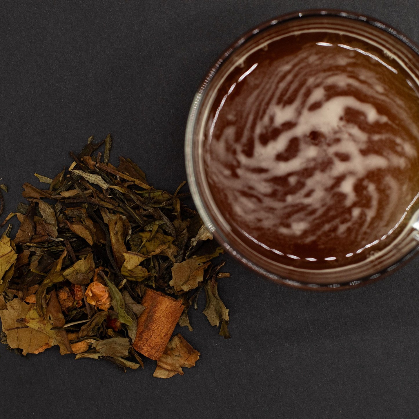 Eternal Elixir green and white tea blend with cinnamon, next to a glass of brewed tea.